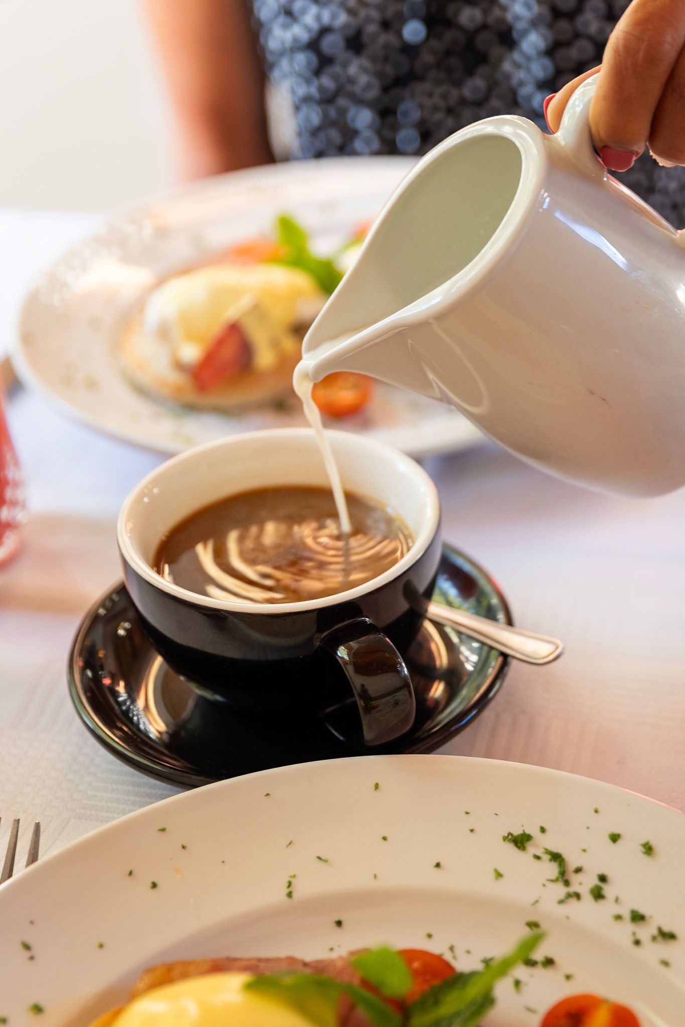 Una persona vertiendo leche en una taza de café.