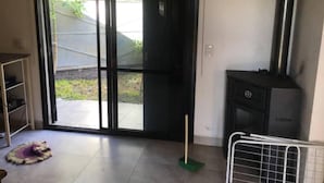 Une pièce dotée d’une porte-fenêtre coulissante donnant sur un jardin, d’une cheminée et d’une étagère en métal.