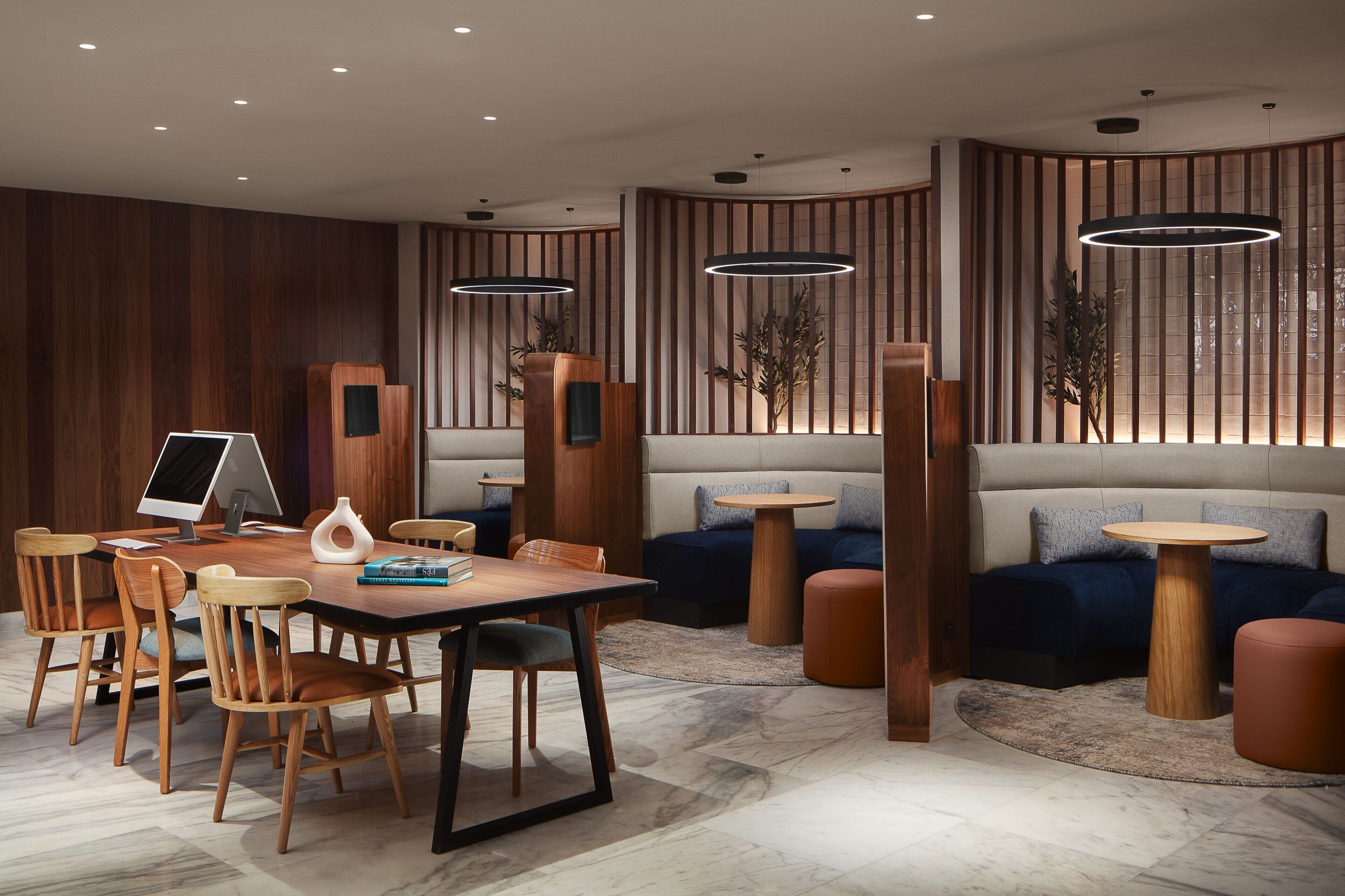 Ein moderner Lounge-Bereich mit Holztisch, Stühlen, einer Couch und einem runden Tisch.