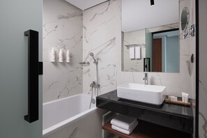 A modern bathroom with a marble wall, a white bathtub, a black countertop, and a large mirror. - Courtyard by Marriott Casablanca Downtown (Casablanca)