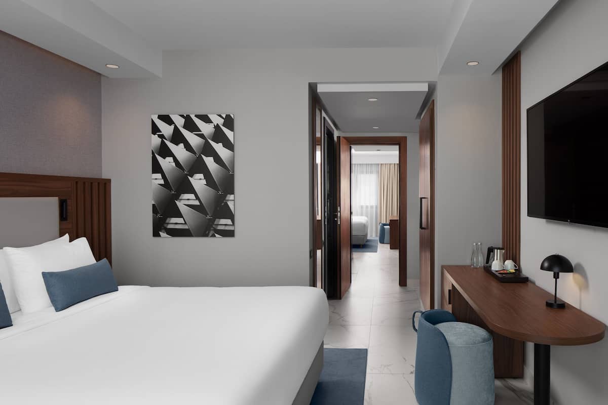 A modern hotel room with a large bed, a desk, and a TV.