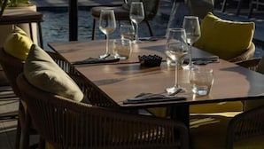 A dining table set for two with chairs, a poolside view, and umbrellas in the background. - Courtyard by Marriott Casablanca Downtown (Casablanca)