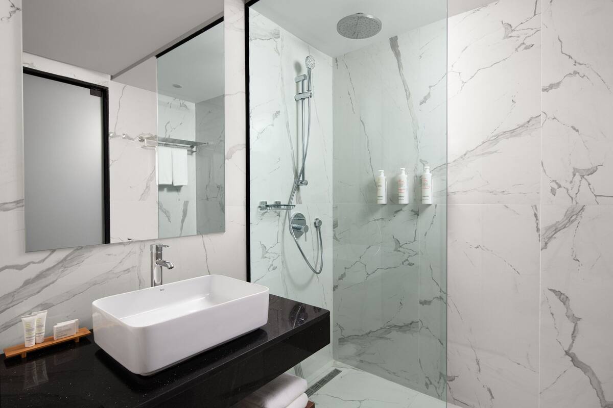 A modern bathroom with a rectangular sink, a large mirror, and a shower enclosure.