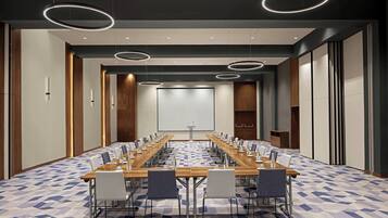 A conference room with a long table, multiple chairs, and a projector screen.
