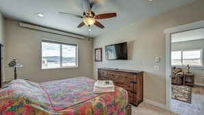 A bedroom with a bed, a ceiling fan, a dresser, a TV, and a view of the outdoors. - Beautiful dog friendly apartment! STR-243 (Buena Vista)