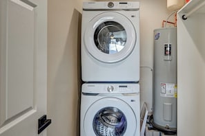A stacked washer and dryer unit with a water heater to the right.