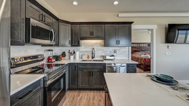 A modern kitchen with dark cabinetry, stainless appliances, and a central island. - Beautiful dog friendly apartment! STR-243 (Buena Vista)
