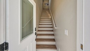 A staircase with wooden steps and a handrail, leading to a door with a glass panel. - Beautiful dog friendly apartment! STR-243 (Buena Vista)