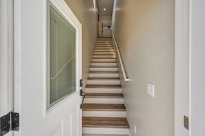 A staircase with wooden steps and a handrail, leading to a door with a glass panel.