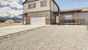 A two-story house with a garage, a stone facade, and a view of mountains in the background. - Beautiful dog friendly apartment! STR-243 (Buena Vista)