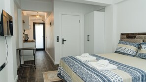 A bedroom with a bed, bedside tables, a TV mounted on the wall, and a door leading to a hallway. - Port Marmaris Rooms (Marmaris)