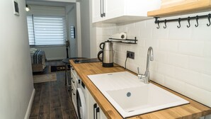 Una cocina compacta con encimera de madera, hervidor de acero inoxidable y un grifo moderno.