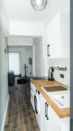 A modern kitchen with a wooden countertop, a built-in washing machine, and a coffee maker. - Port Marmaris Rooms (Marmaris)