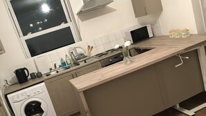 A modern kitchen with a built-in washing machine, a microwave, and a sink. - Charming 3-bed Flat in London (London)