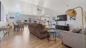 A spacious living area with a sofa, a coffee table, a TV, and a dining area with chairs and a table.