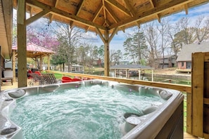 A hot tub with a wooden deck and a view of a residential area.