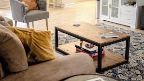 A living room with a sofa, a coffee table, a cabinet, and a patterned rug.