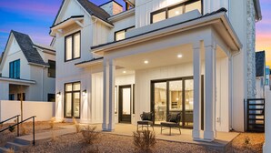 Une maison moderne à deux étages, dotée d’un patio couvert et d’un jardin paysager à l’avant.