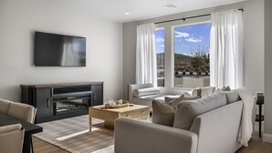 A modern living room with a flat-screen TV, a sofa, a coffee table, and a fireplace.