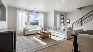 A modern living room with a sofa, a coffee table, and a dining area.