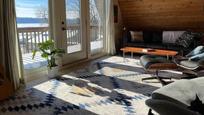 A cozy room with a large window, a wooden ceiling, a sofa, a coffee table, and a potted plant. - Pepin’s Premier Waterfront Stay — The Dockside (Pepin)