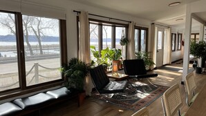 A spacious room with large windows, a bench, chairs, and potted plants. - Pepin’s Premier Waterfront Stay — The Dockside (Pepin)