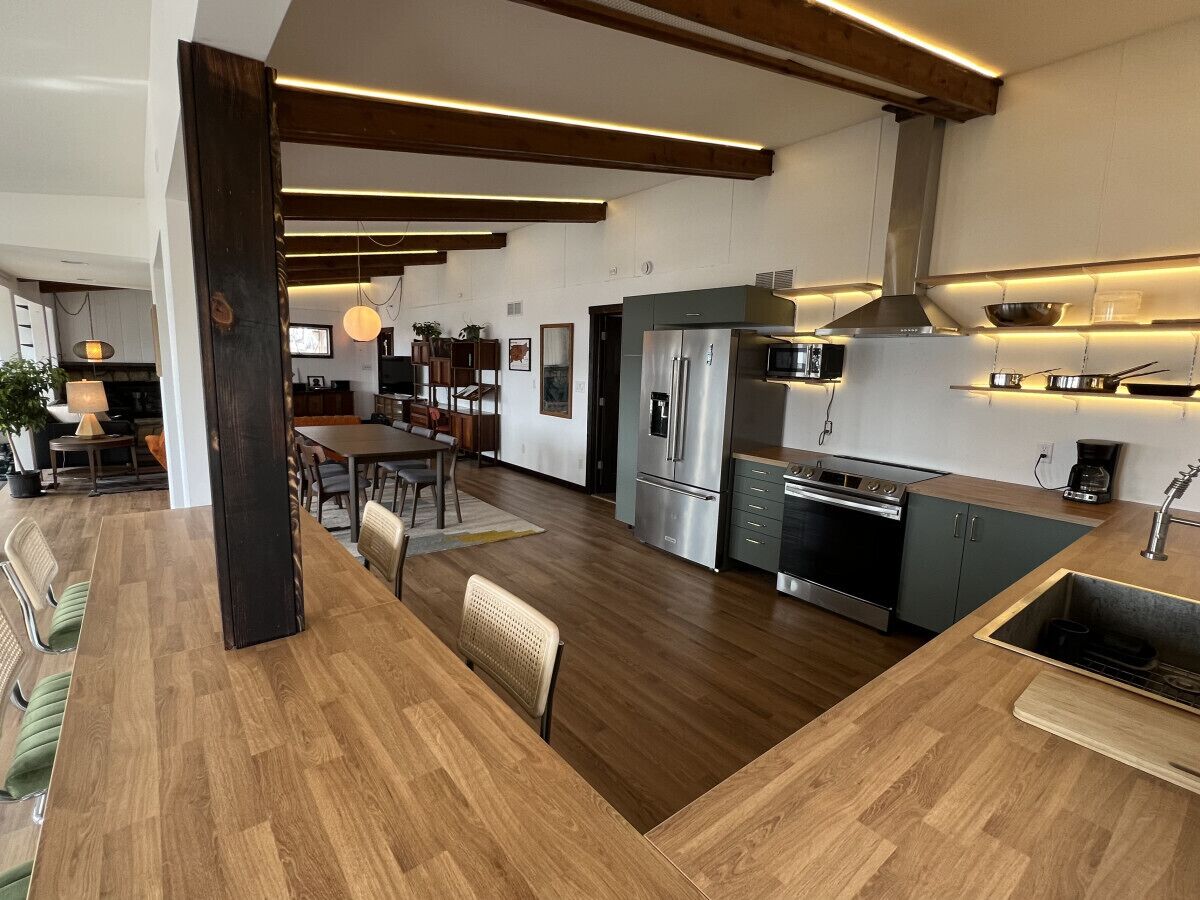 A modern kitchen with a central island, stainless steel appliances, and wooden flooring.