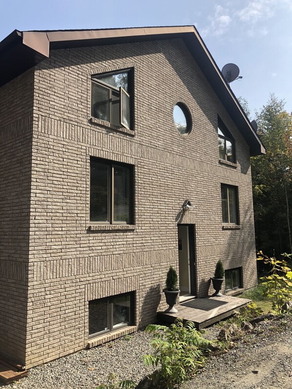 A modern two-story house with a brick exterior, multiple windows, and a satellite dish on the roof.