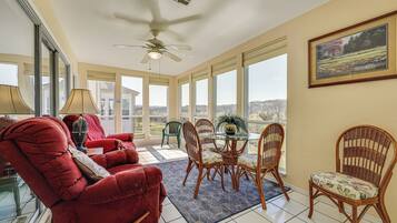 A spacious room with a red velvet sofa, a dining table with chairs, and large windows offering a view of the outdoors.