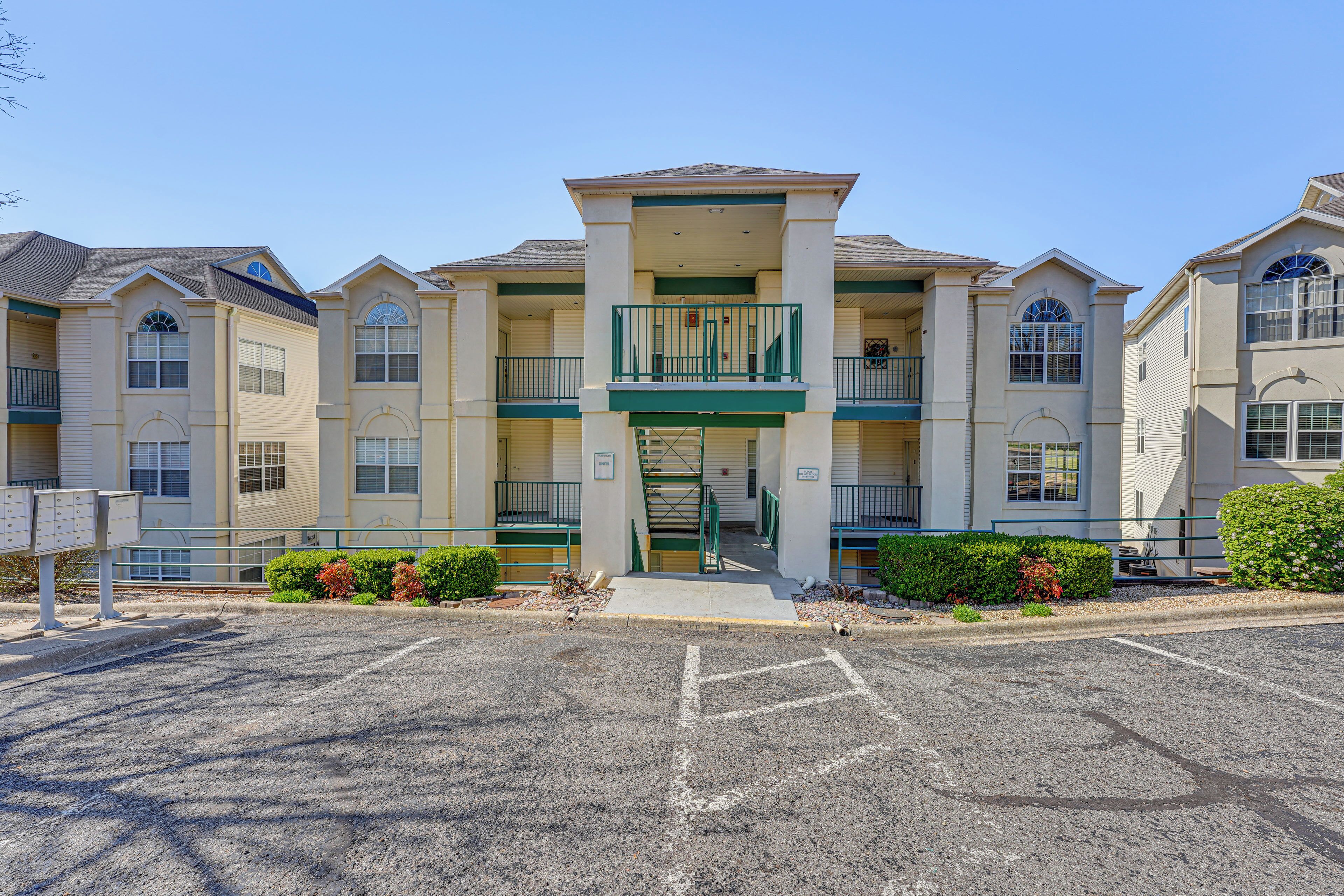 A multi-story hotel with a central entrance, balconies, and a parking lot.