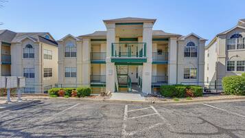A multi-story hotel with a central entrance, balconies, and a parking lot.