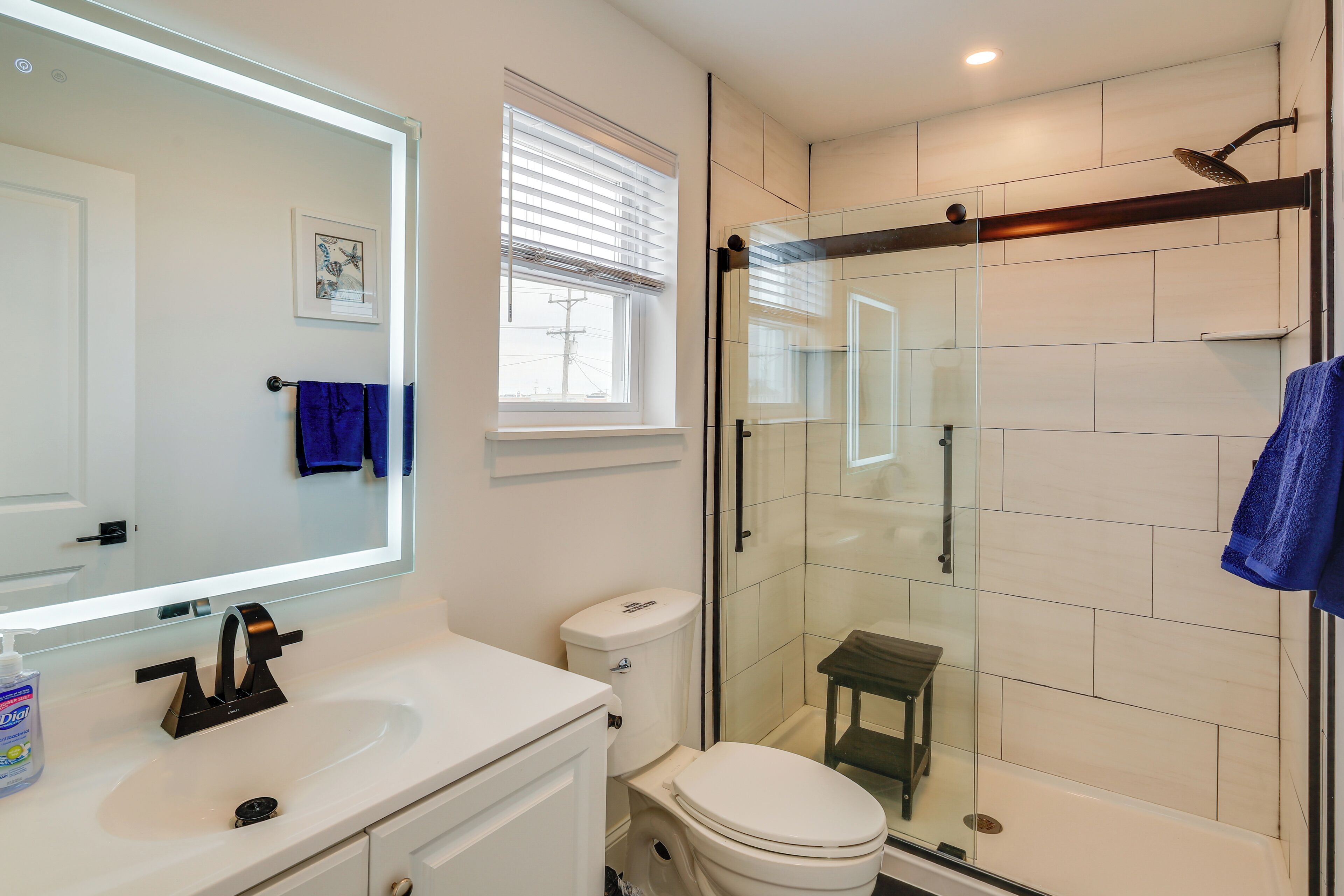 A modern bathroom with a glass-enclosed shower, a white sink, and a toilet.
