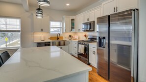 A modern kitchen with white cabinets, stainless steel appliances, and a marble island. - The Kraken Wildwood Townhome: 1/2 Mi to Beach! (Wildwood)