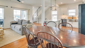 A spacious living area with a dining table, chairs, a sofa, and a staircase leading to an upper level. - The Kraken Wildwood Townhome: 1/2 Mi to Beach! (Wildwood)