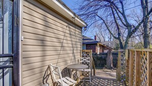 Une terrasse avec une table et des chaises, une clôture en bois et une maison dont le revêtement extérieur est de couleur beige.