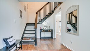 Un escalier en bois foncé, avec des rampes noires, menant à un palier où se trouvent une console et un miroir.