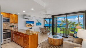 Una cocina moderna con una isla grande, un comedor con vistas y un espacio de sala con un ventanal que da al océano.