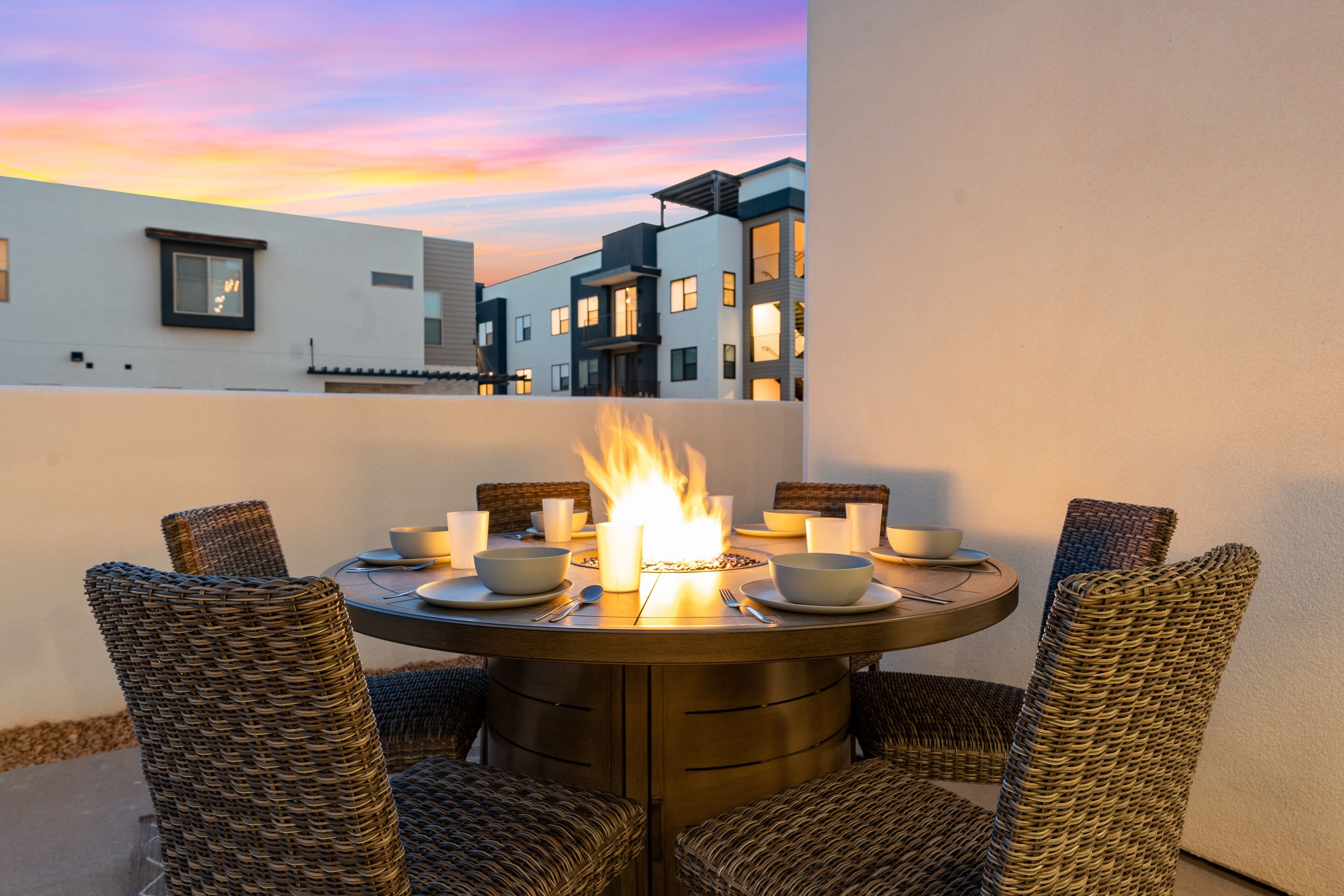 A round table with chairs, a fire, and bowls and cups on it.