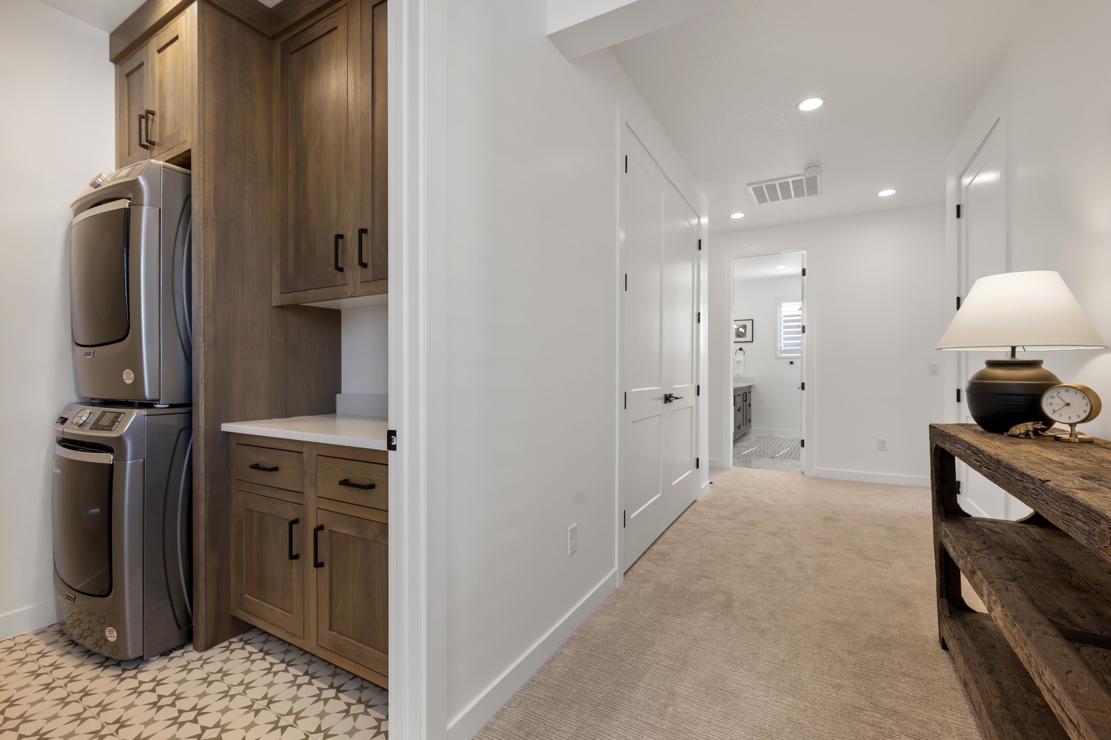 A modern kitchen with built-in appliances, a wooden cabinet, and a hallway leading to a bedroom.