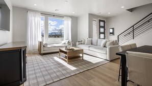 A modern living room with a sofa, coffee table, and a dining area. - Mermaid Lagoon 4 Bedroom Townhouse (St. George)