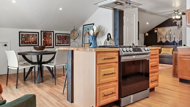 Een moderne keuken met een centraal eiland, een inbouwoven en een eethoek met stoelen.