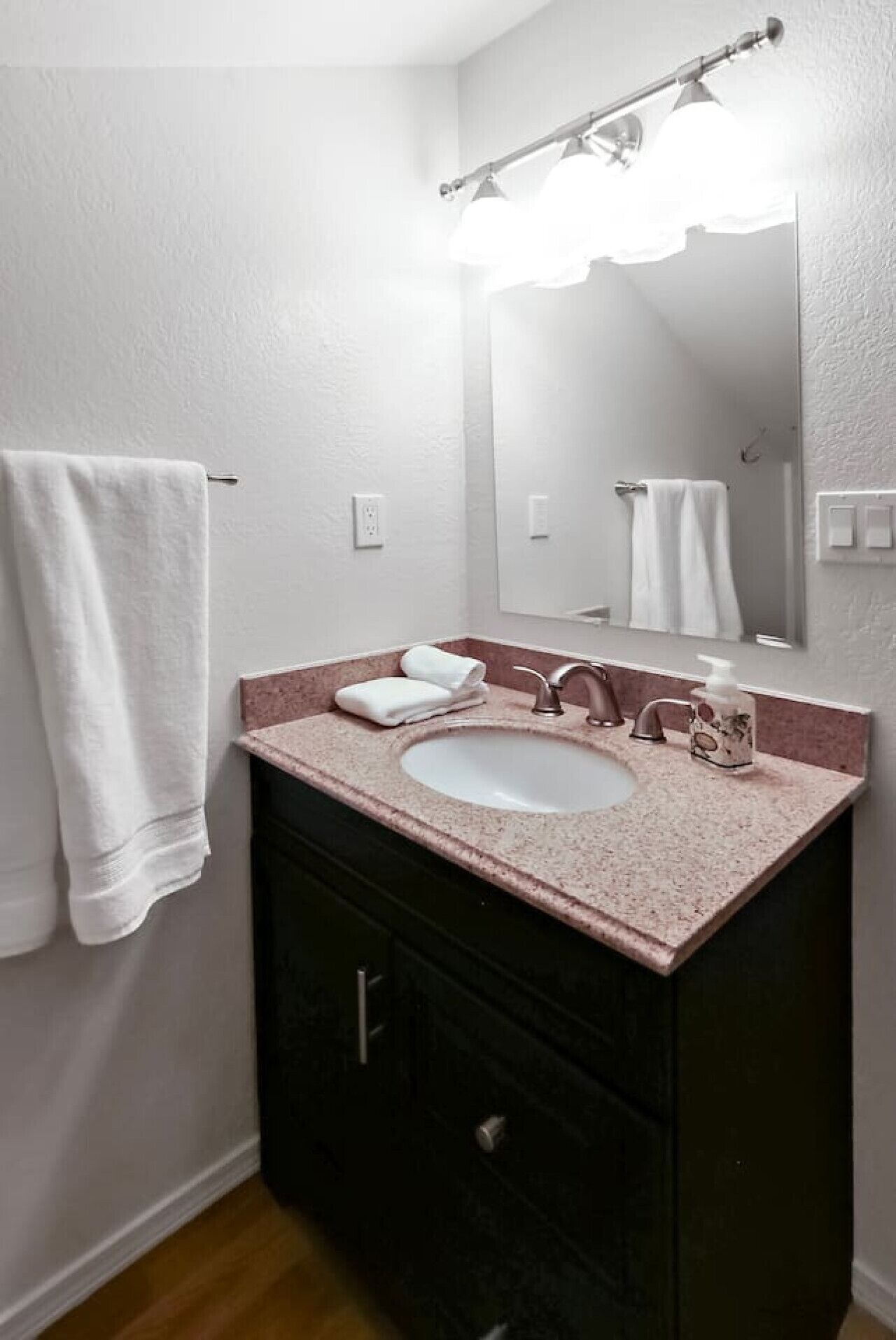 A bathroom with a white sink, a mirror, and a towel rack.