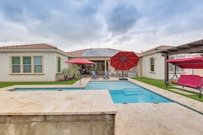 A backyard with a swimming pool, patio furniture, and red umbrellas. - Luxury Queen Creek Home w/ Calming Pool Oasis! (Queen Creek)