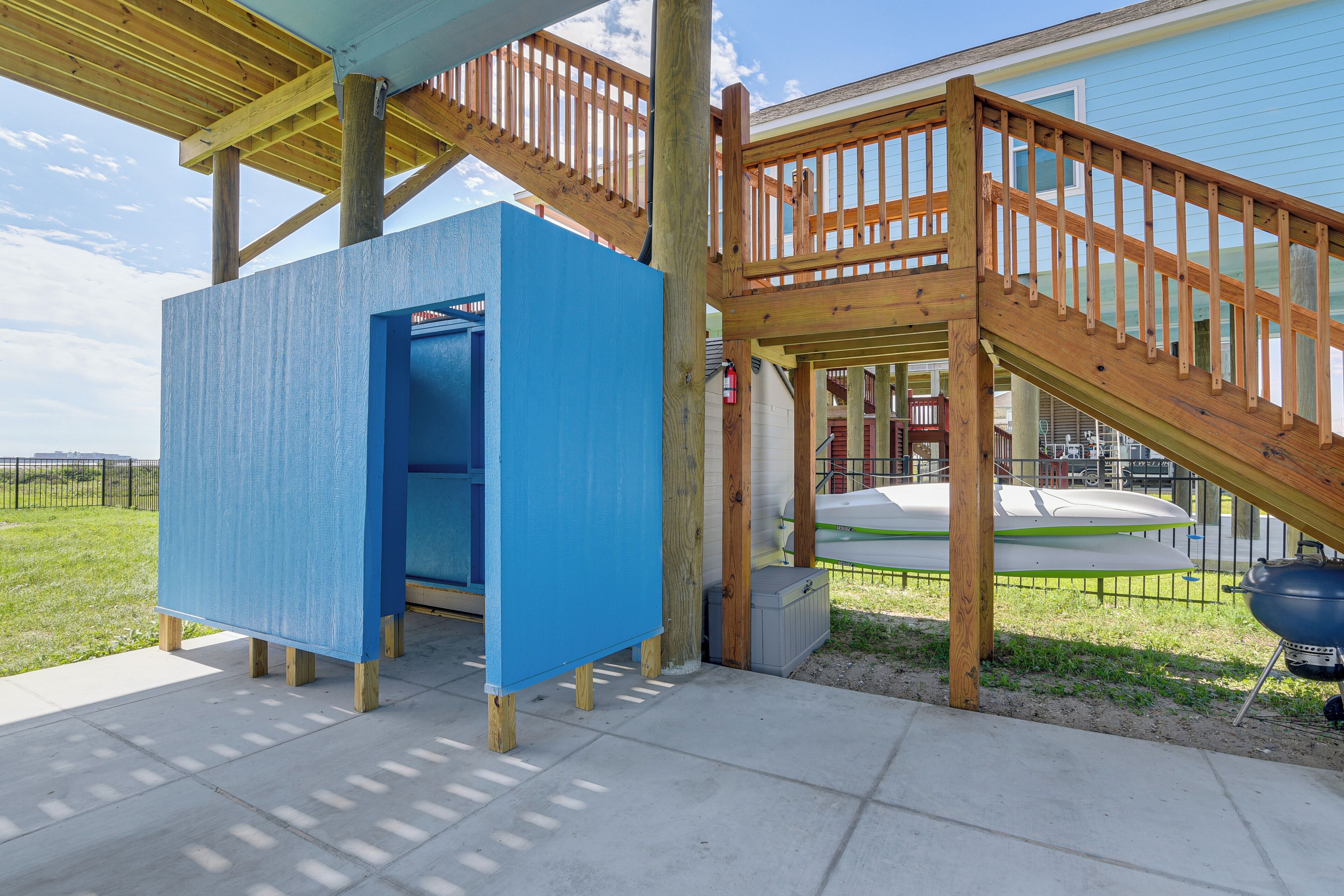 A wooden deck with a blue play structure and a ramp leading to a building.