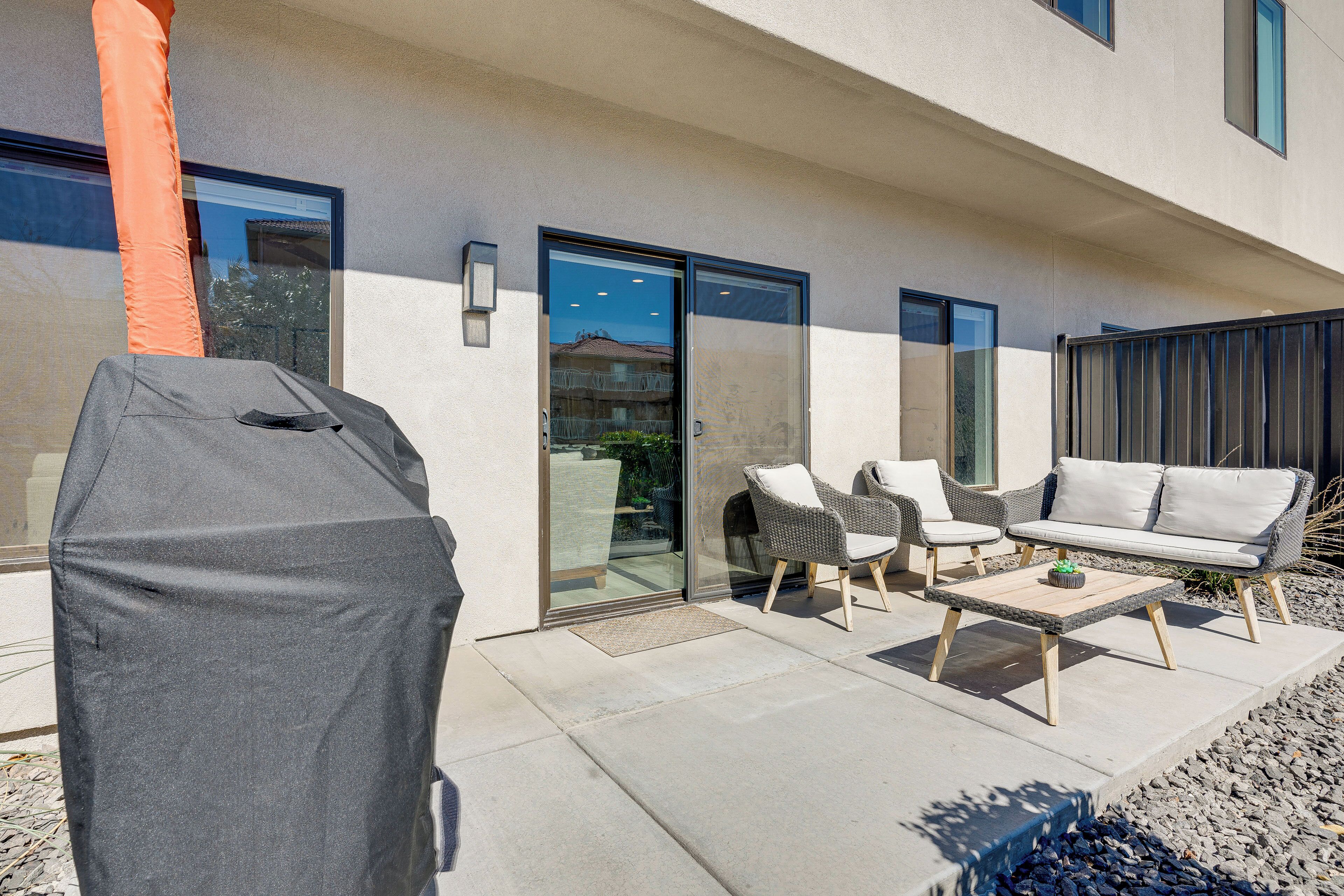 An outdoor patio with a covered grill, wicker furniture, and a sofa.