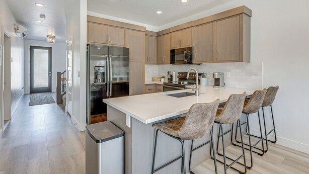 A modern kitchen with wooden cabinets, stainless steel appliances, and a central island with bar stools. - St George Home w/ Patio - 8 Mi to Snow Canyon! (St. George)