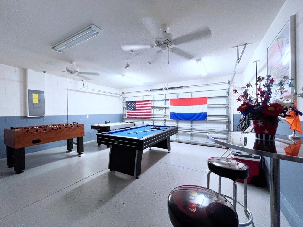 Ein Freizeitraum mit einer Tischfußballplatte, einer Billardtisch, Deckenventilatoren und einer Flagge.