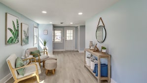 A spacious hallway with a light blue wall, wooden flooring, and a seating area with a chair and ottoman. - Bayfront Maryland Retreat w/ Deck, Near Beaches! (North Beach)