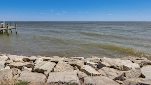 A rocky shoreline with a wooden pier extending into calm waters. - Bayfront Maryland Retreat w/ Deck, Near Beaches! (North Beach)