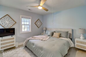 Quarto com cama, ventoinha no teto, televisão e decoração nas paredes.